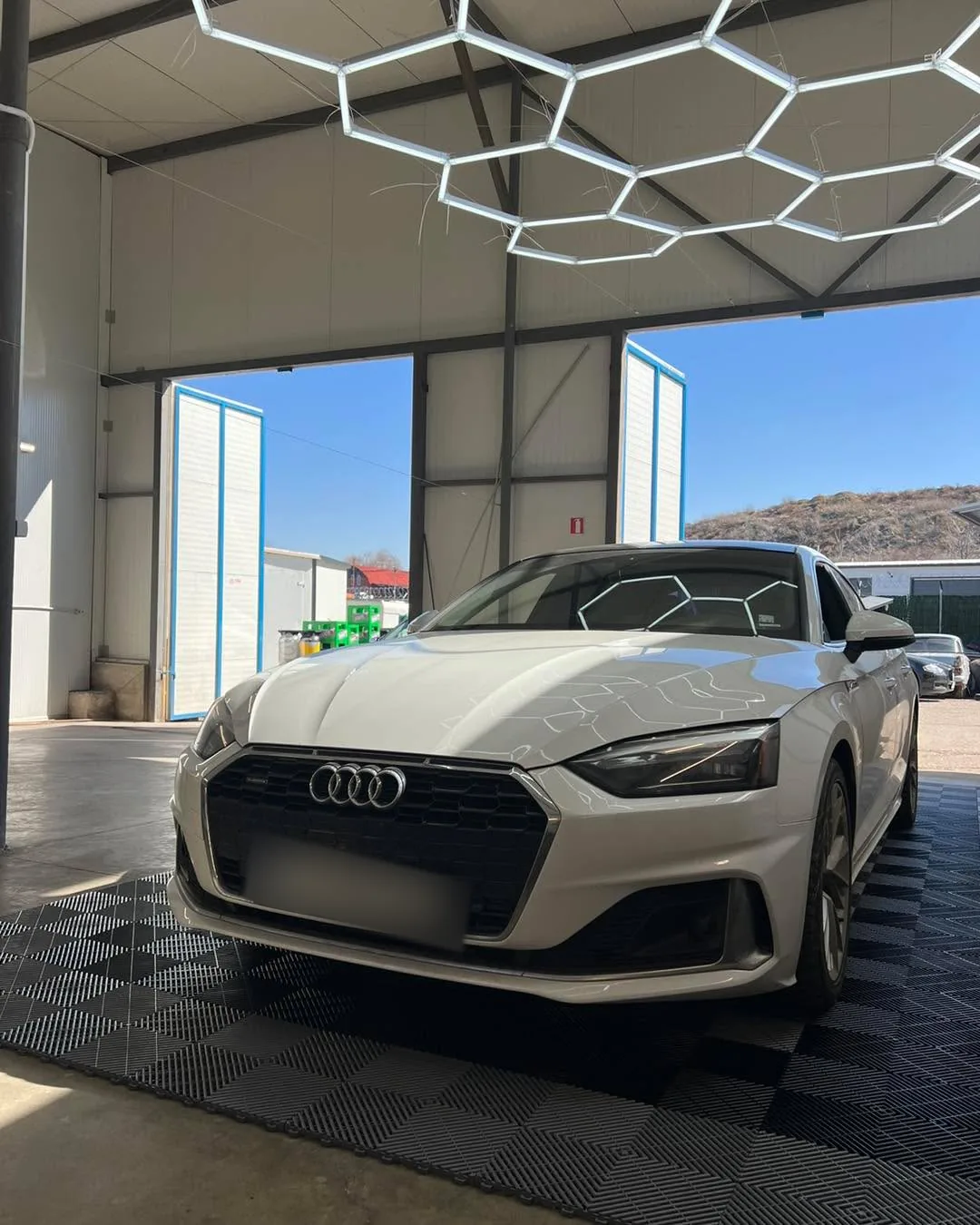 Сребристо Audi A5, заснето отпред под хексагоналното осветление в студиото